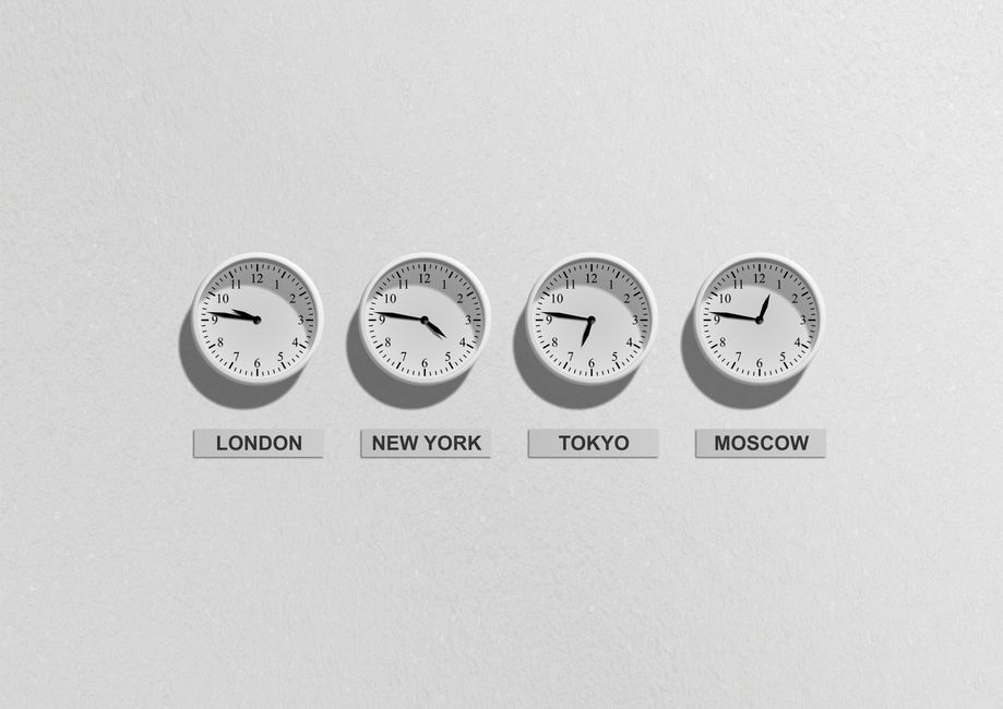A wall of analog clocks at slightly different times in a modern office.
