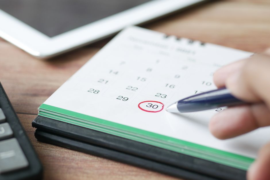 A close-up of a desk calendar with a circled date and a red pin.