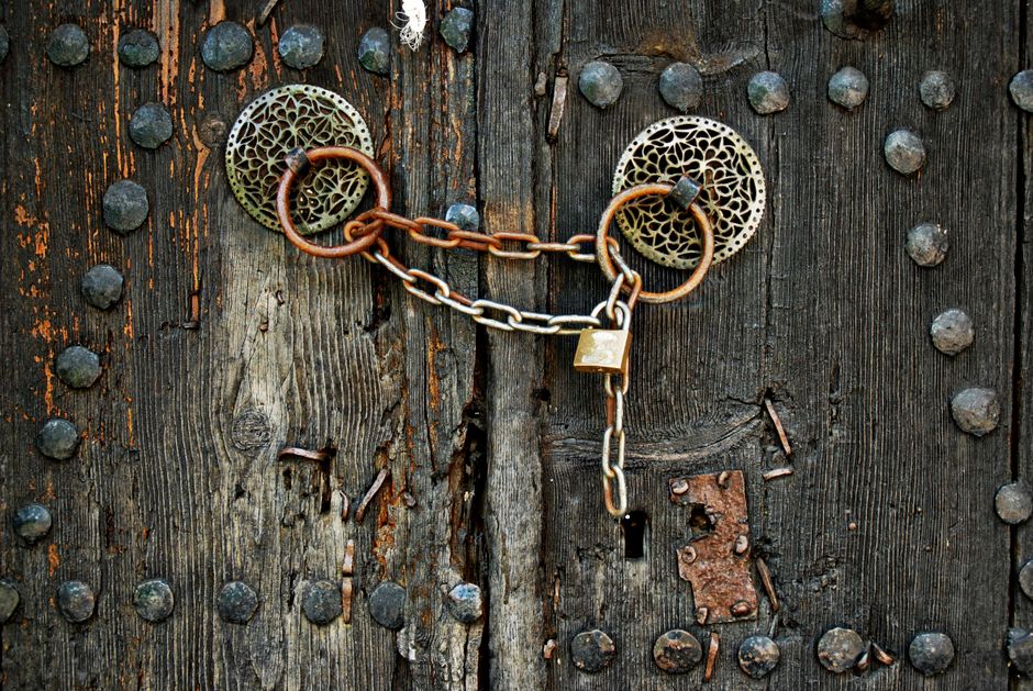A vintage door lock and key on a wooden surface with shallow depth of field.