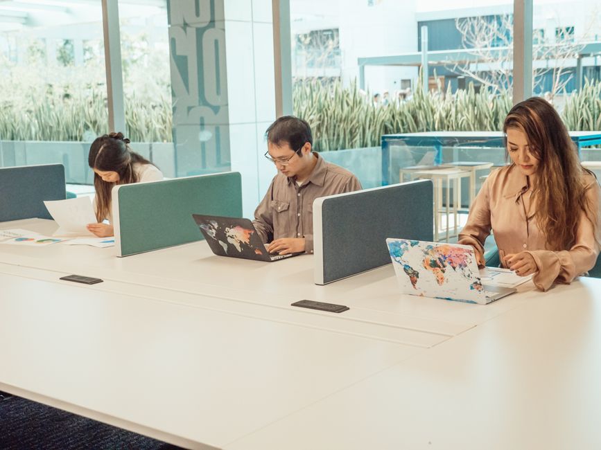Three workspaces with branded laptops in a co-working office.